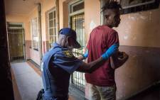 A man is searched by police inside a hijacked building during Operation Fiela 2. Picture: Thomas Holder/EWN