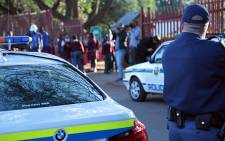 A police officer looks on as Roodepoort Primary pupils arrive back for class after violent protests by parents left the school closed for several weeks. Picture: Reinart Toerien/EWN.
