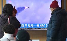 People watch a television screen showing a news broadcast with file footage of a North Korean missile test, at a railway station in Seoul on 27 February 2022.