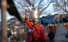 FILE: A woman carries her pots and cooking utensils to market. Picture: AFP