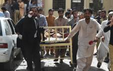 Pakistani lawyers and local media personnel carry a bed to move the body of a news cameraman after a bomb explosion at a government hospital premises in Quetta on 8 August, 2016. Picture: AFP.
