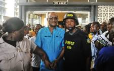 Former deputy governor of the Central Bank of Liberia Charles Sirleaf (C), the son of Liberia's former President Ellen Johnson Sirleaf, is escorted outside the City Court of Monrovia on 4 March 2019, where he appeared in court and charged with economic sabotage following a probe into missing banknotes. Picture: AFP
