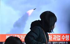 People walk past a television screen showing a news broadcast with file footage of a North Korean missile test, at a railway station in Seoul on 11 January 2022, after North Korea fired a "suspected ballistic missile" into the sea, South Korea's military said, less than a week after Pyongyang reported testing a hypersonic missile. Picture: Anthony WALLACE/AFP