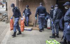 South African police officers confiscate unlawfully sold items at an informal trading post in Hillbrow, Johannesburg, on 28 March 2020 during the second day of the country's lockdown. Picture: AFP