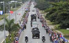 People line the road to see the convoy carrying the urn with the ashes of Cuban leader Fidel Castro as it drives through Sancti Spiritus, Cuba, on 1 December, 2016 during its four-day journey across the island for the burial in Santiago de Cuba. Picture: AFP.