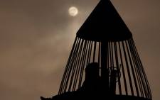 The moon shines though clouds as people sit inside a rocket ship-themed playground tower before a lunar eclipse on November 18, 2021 in Torrance, California. Picture: Patrick T. FALLON / AFP