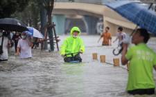 This photo taken on 20 July 2021 shows a man riding a bicycle through flood waters along a street following heavy rains in Zhengzhou in China's central Henan province. Picture: STR/AFP