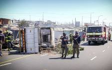 Police stand guard over firecrews that were busy dousing the truck and shack that burnt during protests in Khayelitsha over illegal electricity connections. Picture: Thomas Holder/EWN