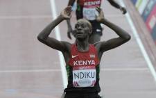 Kenya's Caleb Mwangangi Ndiku raises his hands as he crosses the finish line to win the final of the men's 5000m athletics event at Hampden Park during the 2014 Commonwealth Games. Picture: AFP.