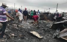 Dunoon residents clear the piece of land where their houses once stood following a fire on 13 March 2018. Picture: Shamiela Fisher/EWN.