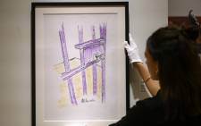 A worker holds a sketch by Nelson Mandela 'The Cell Door, Robben Island' on 26 April, 2019 in New York City. Picture: AFP