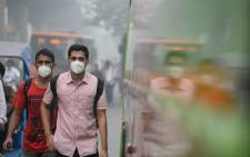 FILE: Indian commuters wear masks as they walk along a road amid heavy smog in New Delhi on 9 November 2017. Picture: AFP