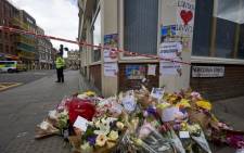 A Police officer stands on duty beyond flowers laid at a cordon on Borough High Street, near Borough Market in London on 5 June 2017, as they continue their investigations following the 3 June terror attack. British police made several arrests in two dawn raids following the 3 June London attacks, claimed by the Islamic State group which left seven people dead. Picture: AFP.
