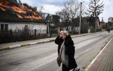 A woman reacts as she stands in front of a house burning after being shelled in the city of Irpin on 4 March 2022. 
