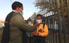 FILE: A teacher takes the temperature and sanitises the hands of a pupil returning to Olivenhoutbosch Secondary School on 8 June 2020. Picture: Gauteng Provincial Government.