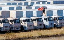 A driver installs a red flag on his lorry, parked with other lorries of the Russian humanitarian convoy not far from a checkpoint at the Ukrainian border some 30 km outside the town of Kamensk-Shakhtinsky in the Rostov region, on 20 August,2014. Picture: AFP.