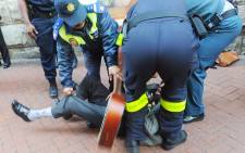 Police drag a blind busker across Greenmarket Square in Cape Town. Picture: Michael Walker/Cape Times