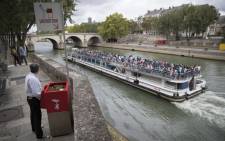 A man stands at a public urinal on 13 August 2018, on the Saint-Louis island in Paris, as a tourist barge cruises past. Picture: AFP.