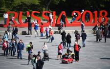 People walk in front of a sign reading Russia 2018 in Yekaterinburg on 12 June 2018, ahead of the Russia 2018 World Cup football tournament. Picture: AFP.