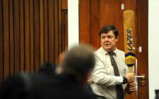 Police forensic expert Colonel Gerhard Vermeulen holds a cricket bat while standing next to the toilet door of murder accused Oscar Pistorius during cross-examination at the High Court in Pretoria on 12 March 2014. Picture: Pool.