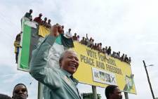 FILE: The late ANC President Nelson Mandela greets young supporters atop a billboard in a township outside Durban, KwaZulu-Natal, on 16 April 1994, prior to an election rally. Picture: Alexander JOE / AFP

