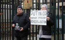 FILE: Protesters hold a caricature showing Russian President Vladimir Putin (L) and a placard reading 'Putin&Co lie and steal - boycott the elections' in front of the Russian Embassy in Paris on 28 January 2018, during a rally called for by Russian political activists in support of Russian opposition leader Alexei Navalny. Picture: AFP.