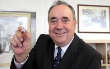 Alex Salmond, Scotland's leader of the Scottish National Party (SNP) and first minister, holds a pin with the Scottish flag during a visit to the Barrie Knitwear factory in Hawick, Scotland. Picture: AFP.