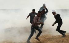Palestinian protesters run from tear gas fired by Israeli forces during clashes following a protest along the border with Israel, east of Gaza City on April 3, 2018 A Palestinian was shot dead by Israeli forces on the Gaza border, the health ministry in the strip said, as tensions remained days after 17 people were killed when a mass demonstration led to clashes. Picture: AFP.
