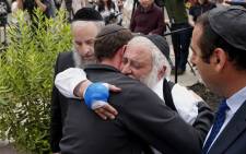 Executive Director Rabbi Yisroel Goldstein (2nd R), who was shot in the hands, hugs his congregants after a press conference outside the Chabad of Poway Synagogue on 28 April, 2019 in Poway, California. Picture: AFP