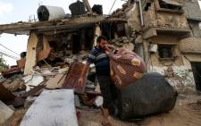 Palestinians salvage belongings from the rubble of their home, following Israeli air strikes in Gaza City, on August 7, 2022. Picture:MAHMUD HAMS / AFP