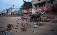 A man drives a motorcycle past rubbles at dusk in the main avenue of Beni following a demonstration against the postponement of elections in the territory of the Beni and the city of Butembo, on 27 December 2018. A DR Congo opposition bloc called for a nationwide stoppage and police clashed with demonstrators in two eastern cities after upcoming elections were placed on hold in their region. Picture: AFP