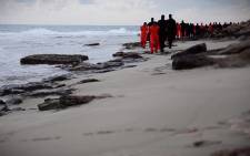 An image grab taken from a video released by the jihadist media arm Al-Hayat Media Centre on 15 February, 2015 purportedly shows black-clad Islamic State (IS) group fighters leading handcuffed hostages, said to be Egyptian Coptic Christians, wearing orange jumpsuits before their alleged decapitation on a seashore in the Libyan capital of Tripoli. Picture: AFP