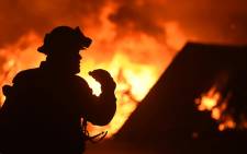 A firefighter drinks water in front of a burning house near Oroville, California on 9 July 2017. Picture: AFP