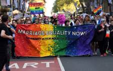 Supporters hold a banner while marching as they attend a same-sex marriage rally in Sydney on September 10, 2017. Picture: AFP.