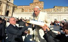 Pope Francis blows out the candles of a birthday cake to celebrate his 78th birthday during a general audience at the Vatican on 17 December 2014. Picture: AFP.