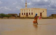 FILE: A Sudanese woman crosses a flooded area, as a result of flooding and torrential rain, in the town of Osaylat, 50 km southeast of the capital Khartoum, on August 6, 2020. Picture: Ashraf Shazly / AFP.
