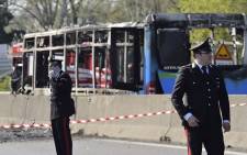 Italian policemen work by the wreckage of a school bus that was transporting some 50 children on 20 March 2019 after it was torched by the bus' driver, in San Donato Milanese, southeast of Milan. Picture: AFP