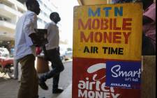 A photograph made available on 22 February 2016 shows people walking in front of a mobile money transfer shop for MTN and Airtel lines in Kampala, Uganda, 17 February 2016. EPA/Dai Kurokawa.