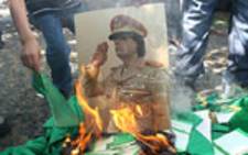 A portrait of Libyan leader Muammar Gaddafi is set on fire by demonstrators during a protest outside the Libyan embassy in Ankara on August 22, 2011. Picture: AFP