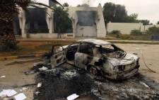 FILE: The wreckage of a burnt car is seen outside a building in Benghazi. Picture: AFP