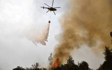 A helicopter pours water on a wildfire on August 5, 2021, near the village of Kechries in North Evia, Greece. Picture: Louisa Gouliamaki / AFP