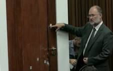 Roger Dixon is pointing out the various cricket bat marks on the door during the Oscar Pistorius murder trial on 15 April 2014.