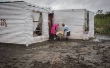 Two women pour out mudwater from their shack after it was wrecked by heavy rains on the N17, Ga Rankuwa, North of Pretoria. Picture: Sethembiso Zulu/EWN