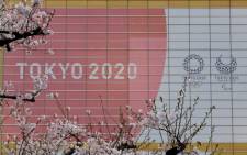 The logo of the Tokyo 2020 Olympic Games and Paralympic Games is displayed behind cherry blossoms in Tokyo on 30 March 2020. Picture: AFP