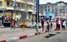 FILE: People stand beside burning objects in the middle of the street on 19 January, 2015 in Kinshasa. Picture: AFP.