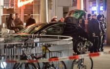 Police officers stand around a car in front of a business building in Heidelberg, western Germany, where a man ploughed into pedestrians before being shot by the police on 25 February, 2017. Picture: AFP.