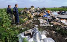 FILE: Employees of the Ukrainian State Emergency Service look at the wreckage of Malaysia Airlines flight MH17 two days after it crashed in a sunflower field near the village of Rassipnoe, in rebel-held east Ukraine, on 19 July 2014. Picture: AFP