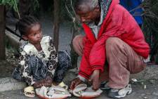 An Oromo girl sits next to a man as they eat donated food on 4 October 2017, at a temporary camp for displaced people outside Adama, Ethiopia. Picture: AFP.