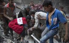 FILE: Syrians surround a man as he cries over the body of his child after she was pulled out from the rubble of a building following government forces air strikes in the rebel held neighbourhood of Al-Shaar in Aleppo on 27 September 2016. Picture: AFP.