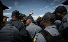 FILE: Police officers surrounded by a crowd. Picture: EWN 